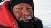 Lähikuva miehen kasvoista. Viikset ovat lumessa ja jäässä.