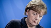 Apean näköinen Angela Merkel katselee alaspäin. 