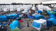 Valkoisia kontteja Calais'n teltoista koostuvan siirtolaisleirin takana Pohjois-Ranskassa.