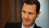 Syyrian presidentti Bashar al-Assad hymyilee. Hänellä on tumma puku.