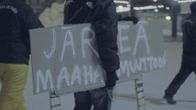 Katupartiolainen kantaa kylttiä, jossa vaaditaan järkeä maahanmuuttoon