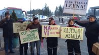 Helsinkiin lähdössä olevat viljelijät seisovat huoltoaseman pihassa ja esittelevät mielenosoituskylttejään.