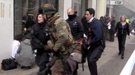 Poliisit ja sotilas kantavat haavoittunutta Maelbeekin metroasemalta ulos.