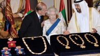 Sheikki Khalifa bin Zayed Al Nahyan esittelee kuningatar Elisabetille ja prinssi Philipille kolmea kaulaketjua ja kunniamerkkejä, jotka ovat samettialustalla. 