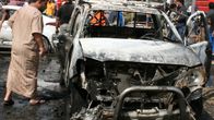 Mies katsoo pommin räjäyttämää autoa Bagdadissa 17. huhtikuuta 2016.