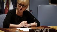 Margot Wallström pöydän ja mikrofonin takana, edessä kyltti, jossa lukee "Sweden". 
