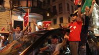 Turkin presidentin Recep Tayyip Erdoğanin kannattajia Istanbulissa. Turkin lippuja piteleviä miehiä roikkuu ulkona kadulla ajavasta autosta. Yhdellä miehistä on myös Turkin lipun kuvalla varustettu paita. Miehet ovat innoissaan ja huutelevat ja hailuttavat lippuja ja käsiään.