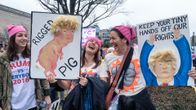 Kolme naista mirrihatuissa pitävät Trumpia pilkkaavia kylttejä: "Rigger pig" ja "Keep your tiny hands off our rights."