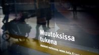 Nainen ja lastenvaunut heijastuvat Kansaneläkelaitoksen toimipisteen ikkunasta.
