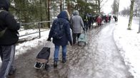 Ihmiset jonottivat elintarvikkeita jäisellä tiellä Helsingin Myllypurossa.