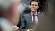 Kushner istuu ja katsoo alaviistoon.