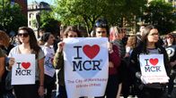 Joukko ihmisiä. Eturivissä olevilla on julisteet, joissa lukee I love MCR, The City of Manchester Stands United.