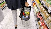 Nainen kantaa kauppakoria ruokakaupassa.