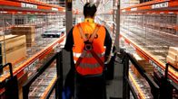 Työntekijä hyllyjen välissä Amazonin uudessa jakelukeskuksessa Wernessä, Saksassa.