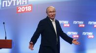 Vladimir Putin puku yllään, levittelee käsiään.