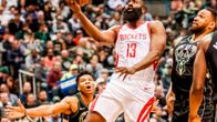 James Harden heittää kahden Milwaukee-pelaajan välistä.