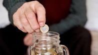 mies pudottaa euroa lasipurkkiin