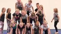 9-10-vuotiaat ovat muodostamassa pramidia, jossa ihmiset ovat kontallaan rivissä ja heidän päälleen tulee aina seuraava rivi. Tässä ihmispyramidissa on kolme kerrosta.