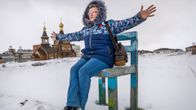 Venäläisrouva Larisa istuu talvimaisemassa kädet levällään.