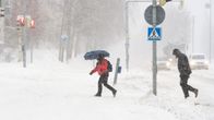 Ihmiset kävelevät lumimyräkässä.