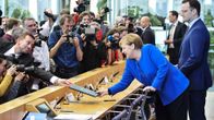 Saksan terveysministeri Jens Spahn ojentaa dokumentteja Angela Merkelille.