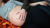 Mies pitää kättään odottavan naisen paljaalla vatsalla.