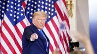 Yhdysvaltain presidentti Donald Trump osoittaa kameraa, taustalla Yhdysvaltain lippuja