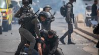 Kuvassa kaksi poliisia on painanut palestiinalaisen miehen katuun. 