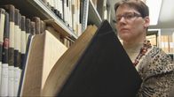 Tuija Korhonen katsoo arkistossa kirkonkirjaa