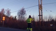 Korjausmies puhuu kännykkään tien laidalla sähkölinjan alla