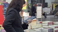Nainen lukee kirjan takakantta kirjakaupassa