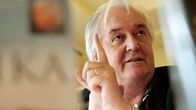 Henning Mankell  vasen etusormi pystyssä, kuvattuna kahden kirjankannen välistä.
