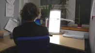 Mies istuu kirkasvalolampun loisteessa. 
