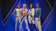 ABBA-yhtye kokonaisuudessaan kuin kultaisella 70-luvulla. Yhtyeellä on vaaleat vaatteet tummansinistä taustaa vasten.
