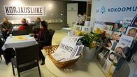Kokoomuksen vaalikahvilassa ihmisiä ja ehdokkaiden esitteitä