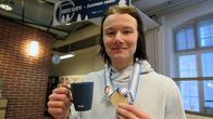 Joni Tuulola mitali kaulassa ja kahvikuppi kädessä
