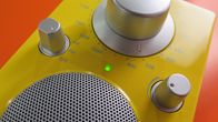 Keltainen radiovastaanotin oranssia taustaa vasten kuvattuna.
