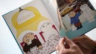 Nainen selailee Mikko Mallikas -kirjaa.