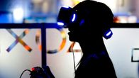 Henkilö virtuaalilasit päässään ja konsoliohjain käsissään.