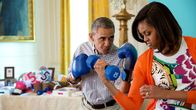 Presidentti Barack Obama hassuttelee nyrkkelyhanskat kädessä vaimonsa Michellen kanssa, joka pitää toisessa kädessään käsipainoa.
