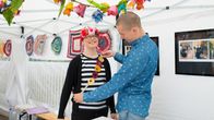 Mies sovittaa koristenauhaa naisen ylle.