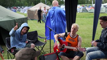 Miehet soittelevat raviradan leirintäalueella.