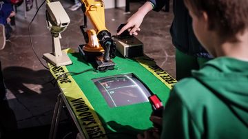 Robottikäsi ja ihminen pelaavat Pongia toisiaan vastaan.
