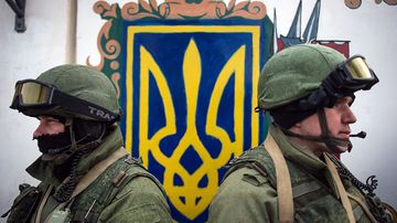 Aseistetut miehet seisovat Ukrainan sotilasyksikön ulkopuolella Perevalnoyessa.