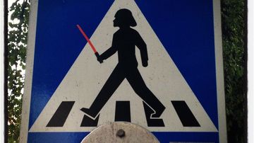 Suojatie-liikennemerkkiin muokattu Star Wars -hahmon päähine ja valomiekka Helsingissä.  Nyttemmin valomiekka on poistettu.