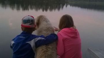 Kaksi lasta ja koira laiturilla.