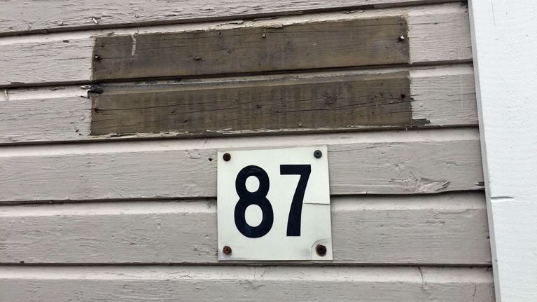 Talon seinä, josta on poistettu kadunnimikyltti. Tilalla on pelkkä tumma jälki.