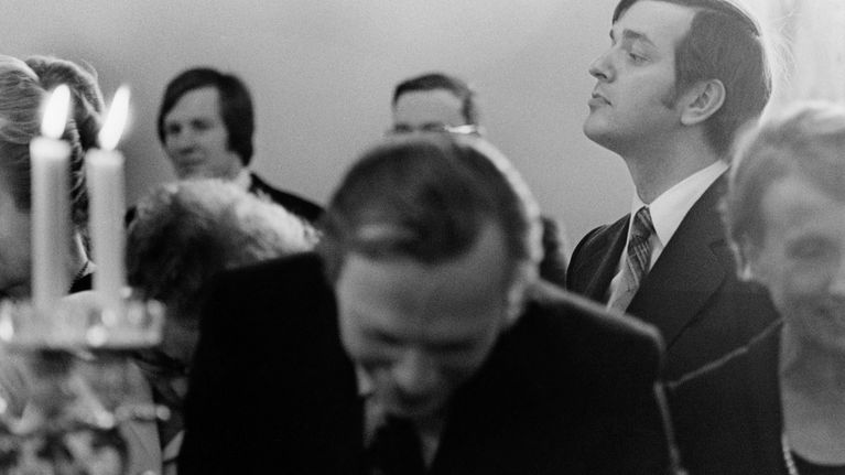 Valtiopäivien avajaiset 1976. Kahvitilaisuus, ministeri Paavo Väyrynen kurottelee toisten yli.