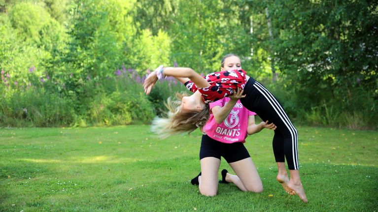 Ohjaaja auttaa oppilasta tekemään akrobatialiikkeen.