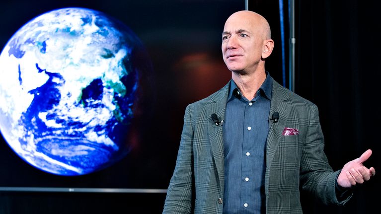 Jeff Bezos pitää puhettaan. Taustalla on maapallo kuvattuna avaruudesta.